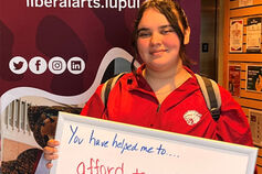 A Liberal Arts student holds a thank-you sign.